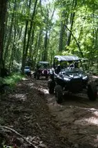 A group of people riding atvs on top of a dirt road.