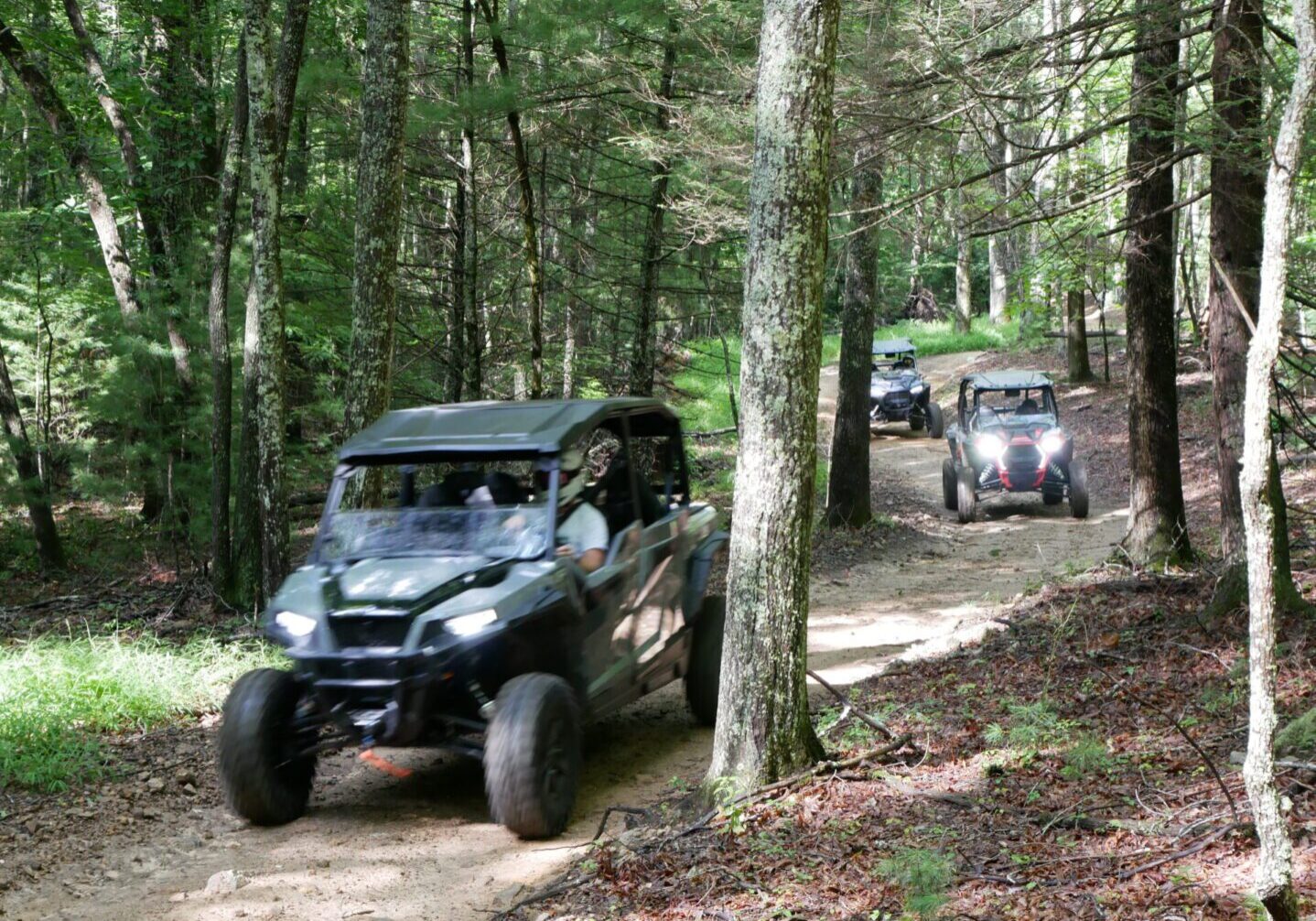 A group of people riding off road vehicles on a trail.